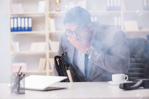 Foto di un lavoratore in ufficio con del fumo che lo fa soffocare