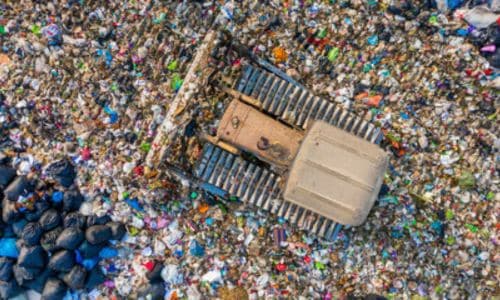 Macchinario di raccolta dei rifiuti che con le ruote cingolate passa opra i rifiuti per raccoglierli e smistarli